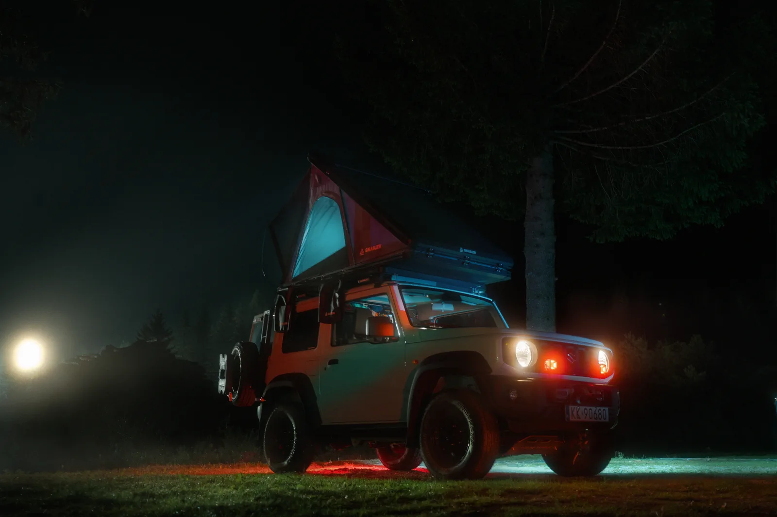 Vehículo todoterreno con una tienda de techo SNAILER iluminada de noche